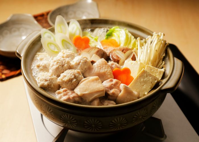 A chanko nabe hot pot filled to the brim with all kinds of fresh vegetables and meats, soaking in a broth.
